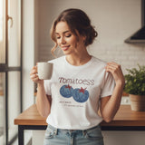 Woman wearing a white tshirt with 'Tomatoess' design, holding a mug in a kitchen