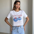 White cropped tee with a blue tomato graphic worn with light jeans
