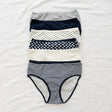Women's navy and white briefs in stripe, dot and heart prints laid flat on a bed