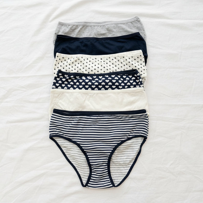 Women's navy and white briefs in stripe, dot and heart prints laid flat on a bed