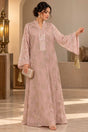 Woman in a blush pink jacquard maxi kaftan with bell sleeves and an embroidered neckline