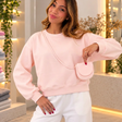 Plain blush pink sweatshirt worn with a matching mini flap pouch on a thin crossbody strap