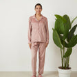 Woman in a blush pink velvet button up PJ set with collared shirt and straight leg pants
