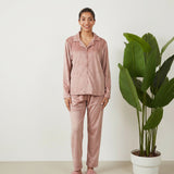 Woman in a blush pink velvet button up PJ set with collared shirt and straight leg pants