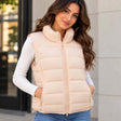 Woman in a blush quilted puffer vest with a high collar over a white ribbed top