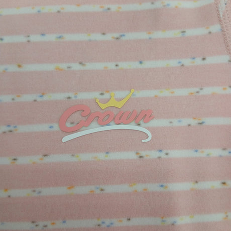 Close up of pink stripe pyjama fabric with confetti flecks and a script chest logo