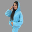 Woman wearing a blue hoodie and sweatpants against a gray background