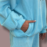 Close-up of a blue jogging set worn by a person with a neutral background