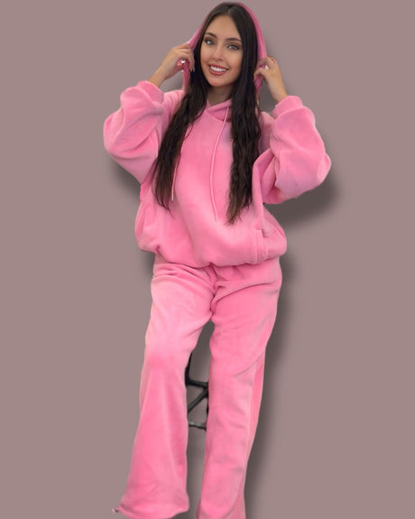 Person wearing a pink jogging set against a plain background