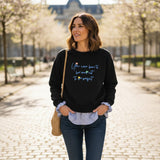 Black crew neck with blue check shirt tail worn outdoors with a woven shoulder bag