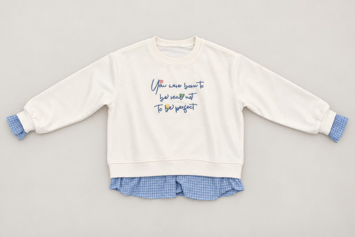 Cream crew neck sweatshirt laid flat with blue embroidered script and gingham trim