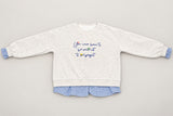 Grey marl crew neck laid out flat, navy script across the chest and blue frills at each wrist
