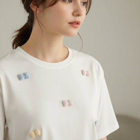 Close view of the pastel bows stitched across a cream tee