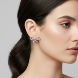 Close-up of a woman wearing a silver bow-shaped earring against a neutral background
