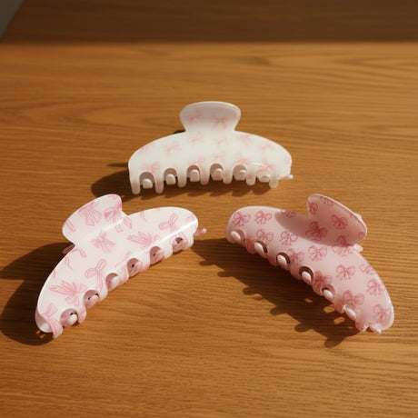 Bow print claw clips in white, pink, and blush pink, curved shape