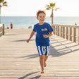 Child running on a wooden boardwalk by the beach