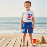 Child wearing a 'Sea Friends' t-shirt and blue shorts on a beach