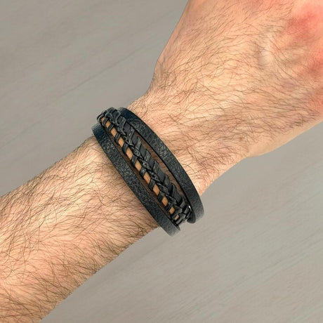 Black leather bracelet with a woven strand over tan cord backing on a wrist