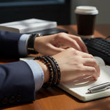 Man in a suit at a desk wearing a brown beaded and braided leather bracelet stack