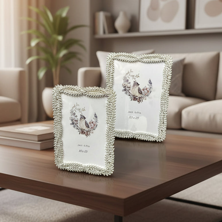 Two silver frames with plaited rope borders and scalloped edges on a walnut table