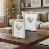 Two silver frames with plaited rope borders and scalloped edges on a walnut table