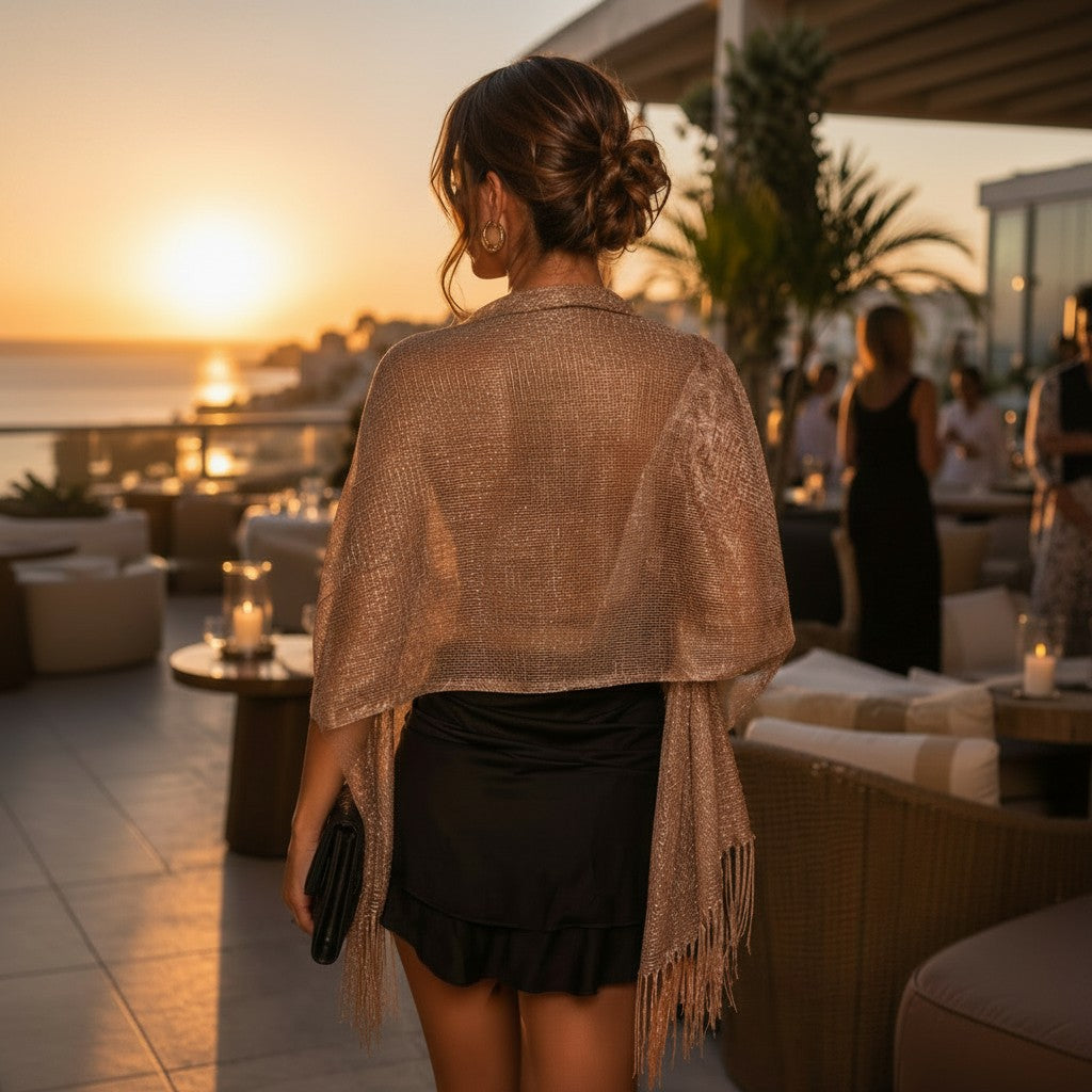 A woman stands on a rooftop terrace wearing a shimmering bronze classy scarf over a black ruffled mini dress