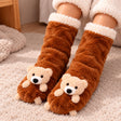 Brown fuzzy socks with a 3D beige teddy bear on each toe and a fluffy cream cuff on a rug