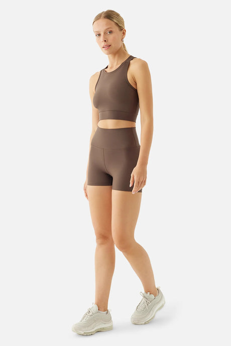 Woman wearing a brown athletic outfit on a white background