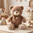 Brown teddy bear plush with a ribbon bow and cream heart paw pads sitting on a rug
