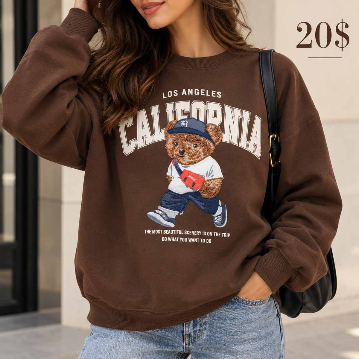 Woman in a brown oversized sweatshirt with a California print and a fuzzy walking teddy bear in a cap