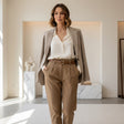Woman wearing brown pants and white shirt with brown blazer standing in a modern interior setting