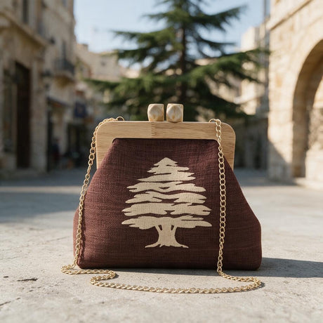 Brown cedar clutch with a wooden frame and gold chain strap on a sunny old town street with a cedar tree