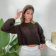 Woman in a chocolate brown chunky ribbed knit cropped sweater with balloon sleeves and a furry headband