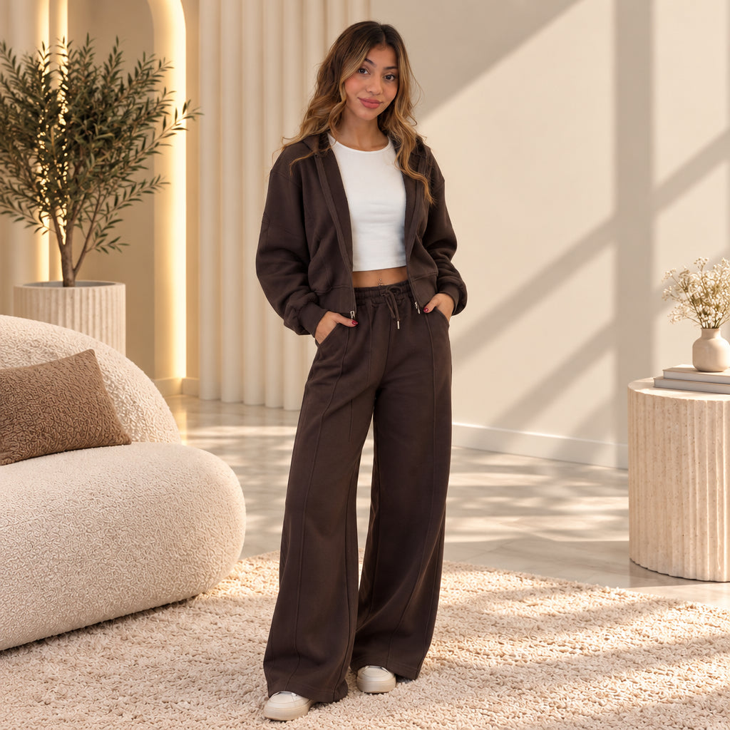 Brown zip hoodie worn open over a white crop top with hands in the front pockets