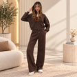 Woman wearing a brown cropped zip hoodie and wide leg pants set with one hand in her hair