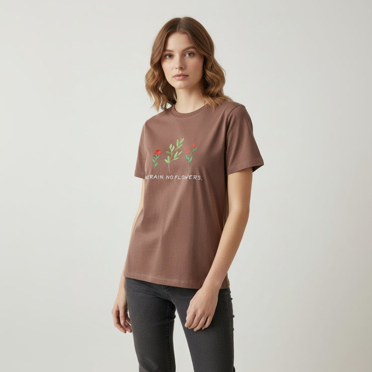 Woman wearing a brown tshirt with floral design and text on a plain background