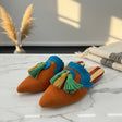 Pair of brown handmade slippers with blue and green tassels on a marble surface
