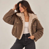 Woman in a brown sherpa collar jacket with gold zip pockets, hand in her jeans pocket