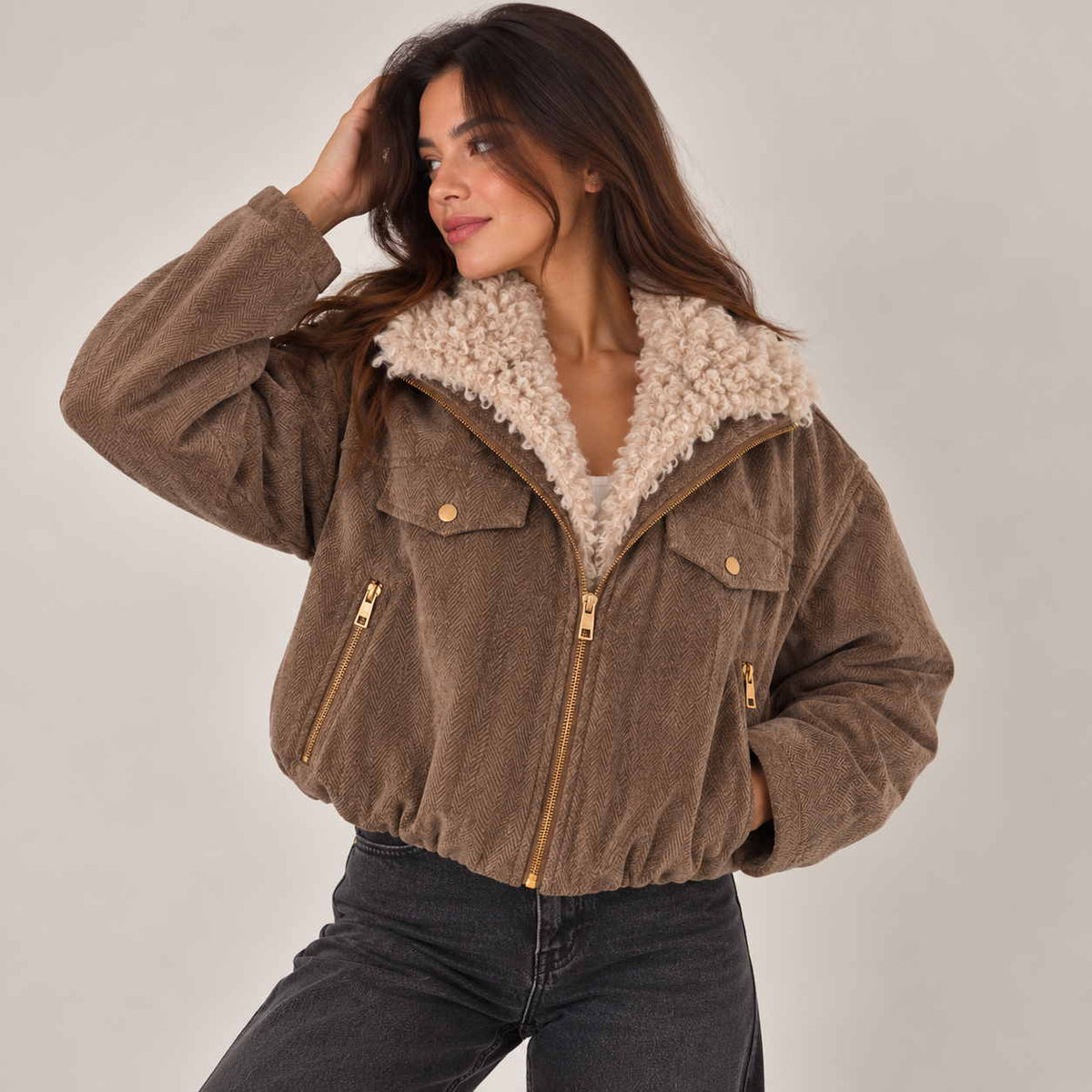 Brown herringbone bomber jacket with cream sherpa collar worn open over a white top
