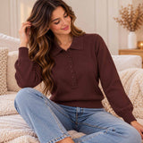 Woman in a chocolate brown knit polo sweater with covered buttons and blue jeans sitting on a knit throw