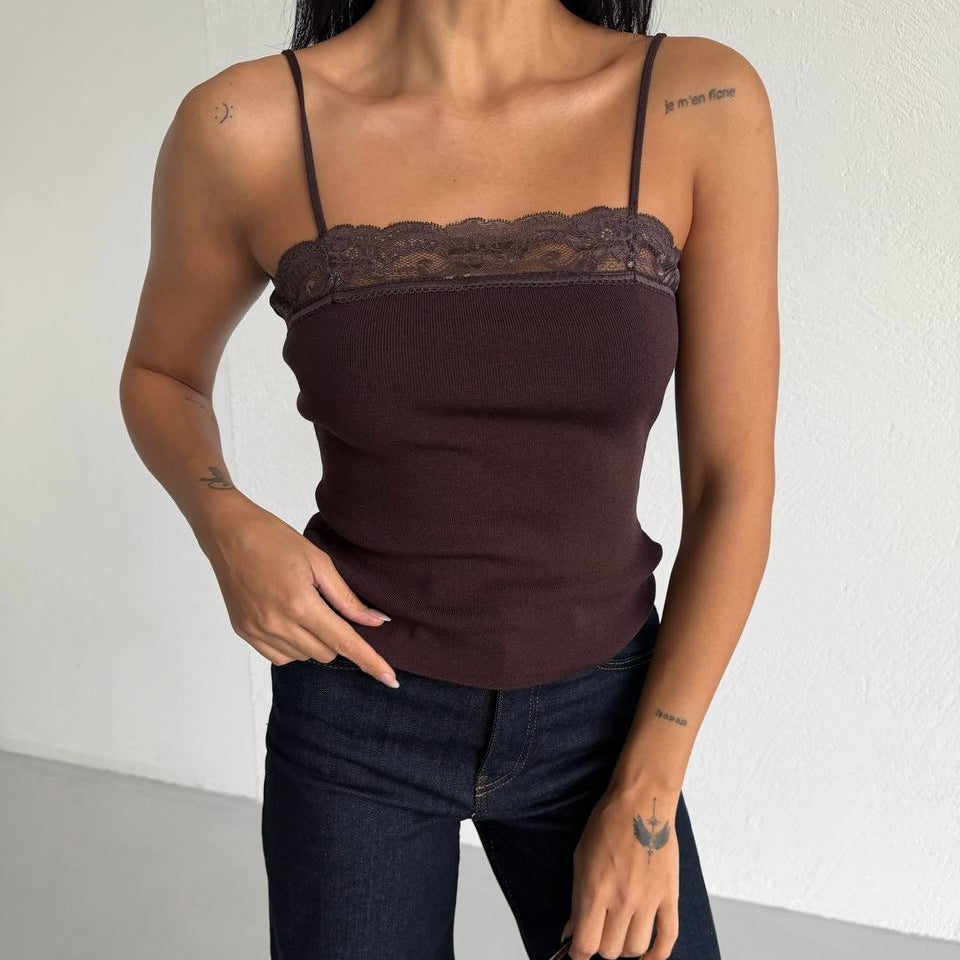 Close up of a woman wearing a brown lace-trimmed top and dark jeans