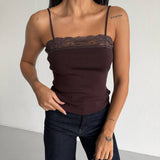 Close up of a woman wearing a brown lace-trimmed top and dark jeans