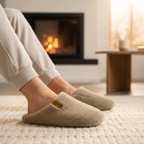 Person wearing beige slippers in a cozy living room with a fireplace