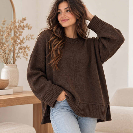 Brown oversized knit sweater with ribbed cuffs and side slits, worn with light blue jeans