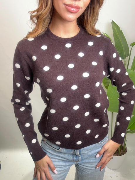 Close up of a dark brown crew neck sweater with white polka dots and ribbed cuffs