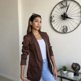 Gathered sleeve detail on a brown blazer viewed from the side