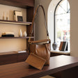 Brown handbag on a wooden surface with a blurred indoor background