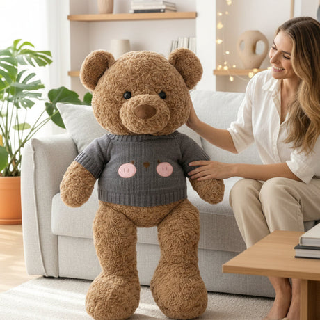 Curly brown teddy bear wearing a charcoal grey ribbed jumper printed with a blush cheeked bear face