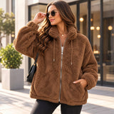 Woman in a brown teddy fleece zip jacket with drawstring collar, black jeans and a black shoulder bag