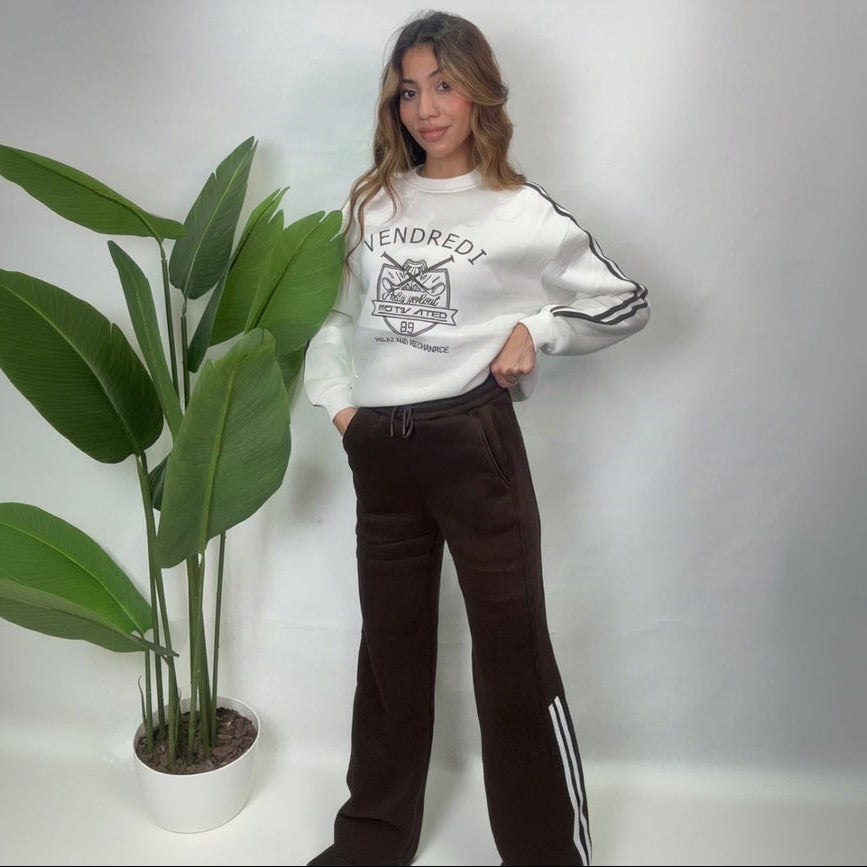 Full length view of a white varsity sweatshirt and brown wide leg pants with white side stripes